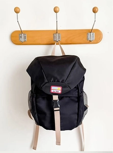 Detail view of black nylon backpack with beige straps and side mesh water bottle pockets