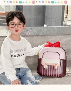 Close-up of pink striped children backpack with a large red velvet bow on a hard shell