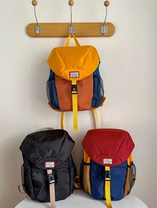 Detail of color-block kids backpacks featuring buckle flaps and mesh side pockets