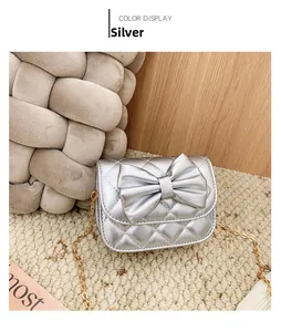 Détail du sac bandoulière argenté matelassé avec grand nœud et chaîne dorée