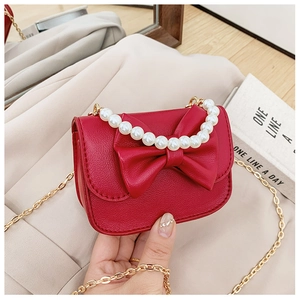 Detail of red PU leather girls bag with large bow, pearl handle and gold chain strap
