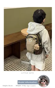 Toddler wearing a cute khaki and green patchwork backpack with a brown bear pendant