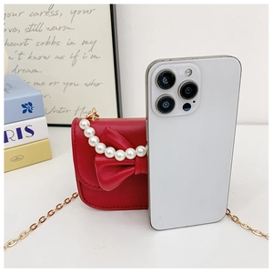 Mini red girls crossbody bag with bow and pearl handle compared to a smartphone for size