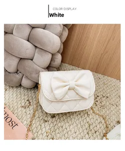Détail d'un mini sac matelassé blanc avec un grand nœud et une bandoulière dorée