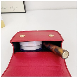 Detail of red pebbled leather mini bag interior showing capacity for lipstick and powder