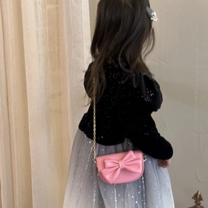 Rear view of a child wearing a pink crossbody bag with a cute bow and metal chain strap