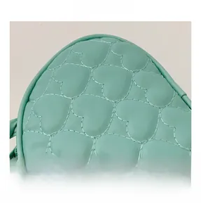 Détail d'un sac à main enfant vert menthe avec coutures matelassées en forme de cœur