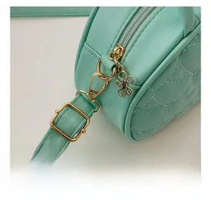 Détail du sac vert menthe matelassé en cœur montrant la fermeture éclair dorée florale