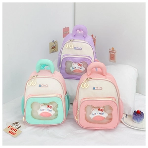 Detail view of macaron colored kids backpacks with cute plush kitten in transparent pocket