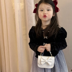 Detail of girls black velvet dress with pearl collar and white bow handbag