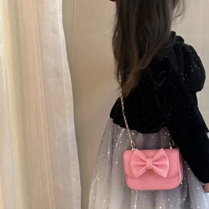 Pink girls bow purse with pearl handle and metal chain shown on a child model