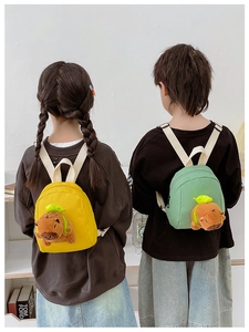 Detail of yellow and green canvas kids backpacks with cute plush capybara charms