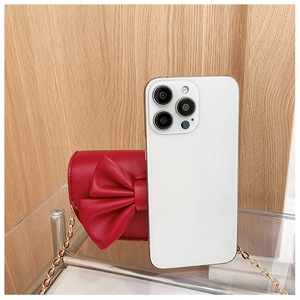 Red mini crossbody bag with bow compared to a phone for size perspective