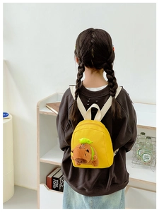Detail of yellow mini toddler backpack featuring a cute plush Capybara doll charm