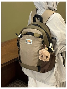 Close-up of children's khaki nylon backpack with mountain embroidery and a plush charm