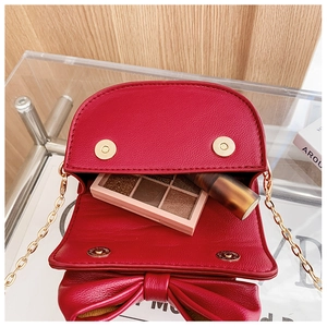 Detail of red mini crossbody bag showing golden magnetic buckles and inner capacity