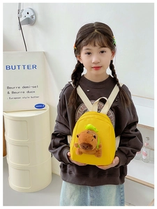 Mini yellow canvas kids backpack with 3D capybara plush doll on a small child model