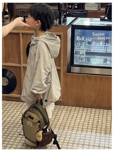 Detail view of children's grey hooded windbreaker with army green hiking backpack