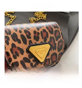 Détail du mini sac léopard avec boucle triangle dorée et bandoulière en chaîne