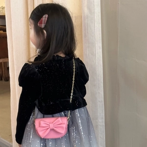 Girl's stylish outfit featuring a black velvet top with a pink bow chain crossbody bag