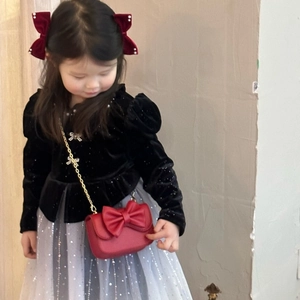 Close-up of a red mini girl's bag with large bow and gold chain on young model
