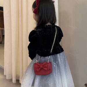Girl's red bow crossbody bag with gold chain strap shown on a young model outfit
