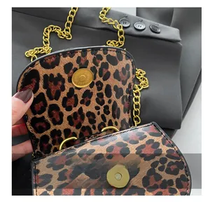 Détail du mini sac léopard montrant la boucle magnétique et la bandoulière chaîne dorée