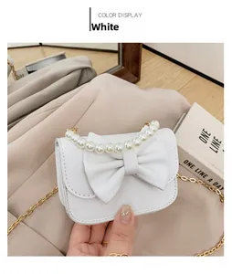 Detail of white girls' purse featuring elegant pearl handle and decorative bow accent