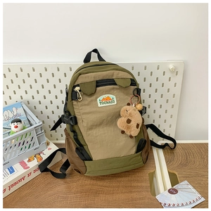 Detail of color-block backpack featuring TOCHASO woven label and cute capybara pendant