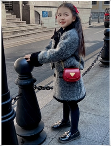 Détail du sac bandoulière rouge avec accent métallique et manteau gris sur l'enfant