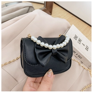Detail of a black faux leather girls handbag with large bow and pearl handle