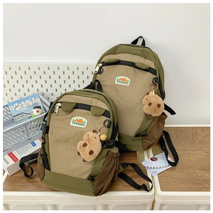 Detail of color-block nylon backpacks with plush animal charms and mountain brand logo