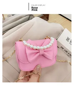 Detail of rose pink girls handbag featuring a large bow, pearl handle, and golden chain strap