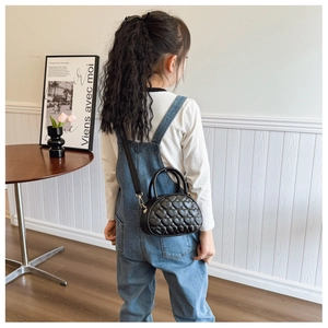 Vue détaillée du sac bandoulière matelassé cœur pour enfant en similicuir noir sur modèle
