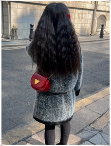 Vue de rue d'un petit sac bandoulière rouge avec logo triangle doré et bandoulière chaîne