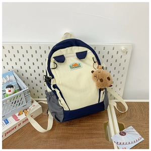 Detail of color-block canvas kids backpack featuring a cute capybara plush keychain