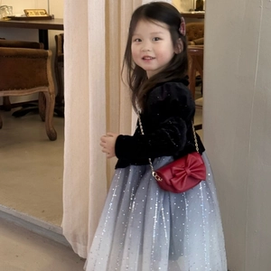 Toddler girl wearing a red mini crossbody bag with a large bow and gold chain strap