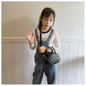 Détail d'un sac à main noir pour enfant avec matelassage en cœur et poignée
