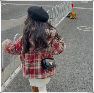 Vue arrière d'un enfant portant un mini sac bandoulière en cuir noir avec boucle dorée