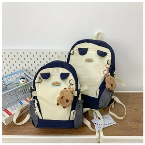 Detailed set of two cartoon backpacks in navy and beige with cute capybara pendants