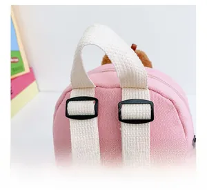 Close-up of adjustable white straps and pink canvas material on the kids backpack