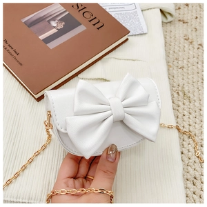 Detailed view of white mini PU leather bag with large bow and gold metal chain strap