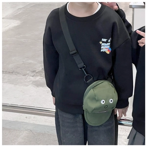 Detail der grünen Mützen-Umhängetasche auf einem schwarzen Kinder-Sweatshirt
