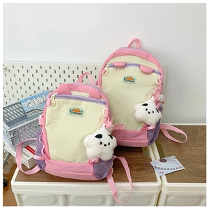 Detail of color-block backpacks in pink and purple with star plush charm and brand logo