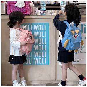 Vue de dos d'enfants portant des sacs à dos lapin rose et chien bleu au café