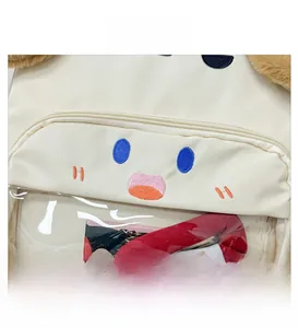 Close-up of cream canvas backpack featuring cartoon dog embroidery and a clear front pocket