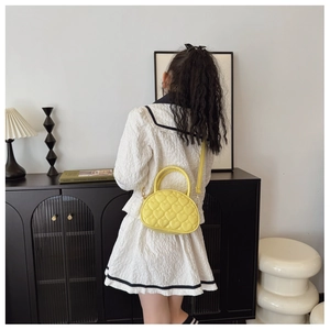 Détail du mini sac à main jaune avec matelassage en cœur, couture chic et bandoulière