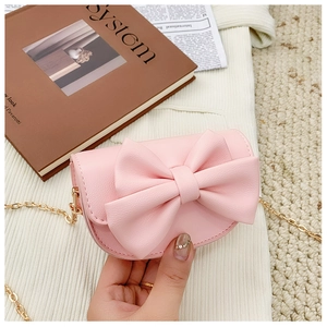 Detail of light pink crossbody bag with 3D bow decoration and gold metal chain strap