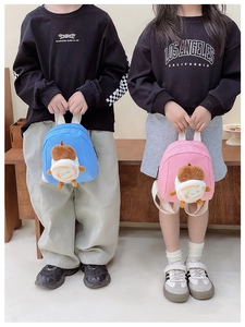 Close-up of mini plush children backpack with cute 3D character charms in pink and blue