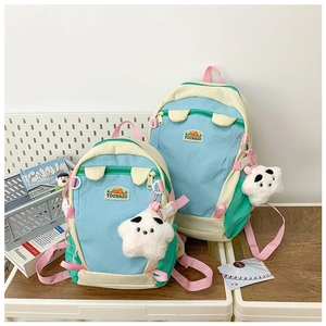 Blue and beige school backpacks with star plush charm on a wooden desk setup